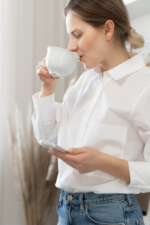 Woman with cup of coffee wearing white poplin shirt
