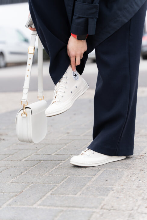 Creamy Converse sneakers with navy-blue trousers